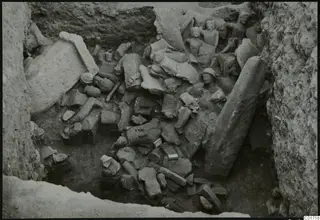 Overview of a pit crowded with broken stone statues and blocks at Kition, with several heads visible at the upper right