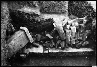 Statues in situ among broken stone fragments in an excavated room at Kition.