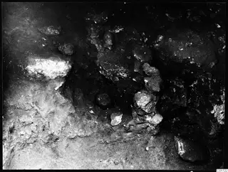 Excavated ground at Kition with pale stones and rounded lumps lying in dark soil