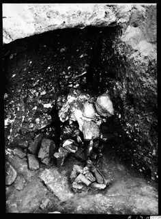 Excavated cutting at Kition with fragmentary pale stone pieces lying in situ against a rock face