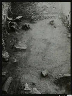 Excavated room at Kition with a bare earth floor, stone walls and scattered stones; no statues clearly visible