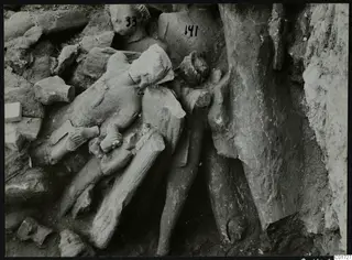 Fragments of stone sculptures lying in excavated soil in the cult room of the large depot at Kition