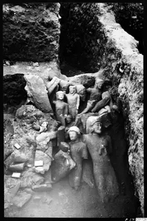 Excavated deposit at Kition with several larger stone sculptures of figures packed among broken blocks