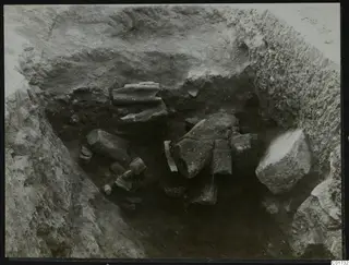 Excavation pit at Kition with broken stone pieces lying in situ among soil and rock.