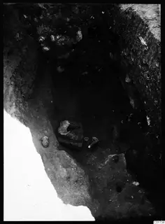 Deep excavation pit at Kition with stone objects and small finds lying in the floor