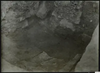 Excavation pit at Kition seen from above, with cut soil walls and stones on the floor.