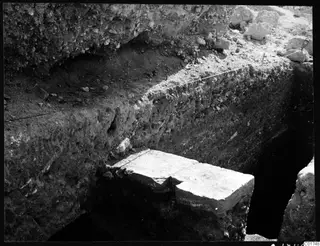 Excavation profile at Kition: a tall soil section above a large pale stone block at the base of a trench