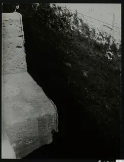 The big profile of the excavation at Kition, showing a deep cut with layered soil walls and a stepped stone-faced ledge.