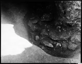 Excavated cutting at Kition showing stones set in soil beside a rock face, the cult room at the north gallery