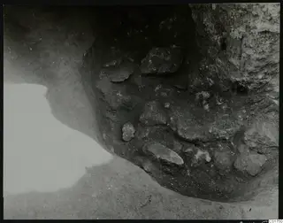 Excavated corner at Kition with stones set in dark soil against a pale rock face