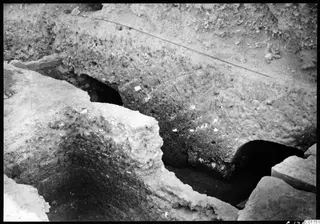 Excavated profile at Kition with two dark openings into galleries at the base of the cult room