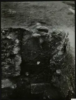 Soil profile in the central pit at Kition, with stone pieces embedded in the face near the top