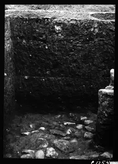 Excavated cult room at Kition seen from the south, with a stone-filled floor and a standing stone block at the right.