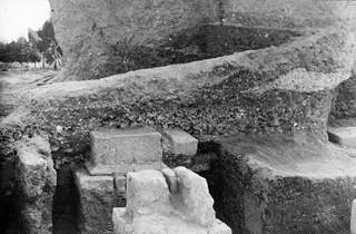 Soil section beside a stone pedestal in the excavation at Kition, with trees at the left edge.