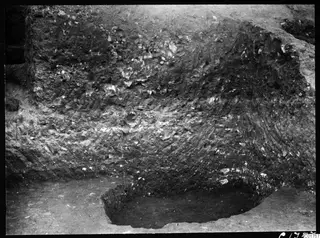 Profile in the eastern part of the Bamboula at Kition, showing layered dark earth and stones, with a hollow at lower right.