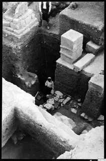 Deep excavation trench at Kition with squared stone blocks and mudbrick walls, with two people at the edge and in the pit.