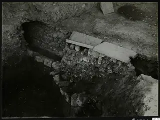Roman water channel at Kition, built of stone and covered with flat slabs in an excavation trench.