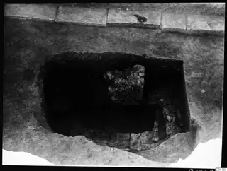 Excavated central pit at Kition, seen from the north, with a block of rubble stones and stone courses inside.