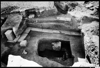 Excavated cult room at Kition seen from the north, with a sunken chamber and long stone slabs along its edge.