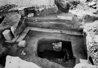 Excavated cult room at Kition seen from the north, with a sunken chamber, stone slabs and loose blocks.