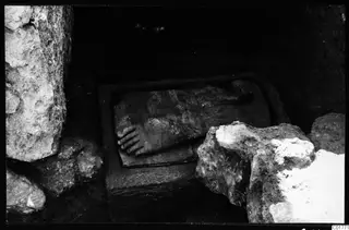 Carved stone figure lying in a stone trough among rock blocks at Kition, Larnaca.
