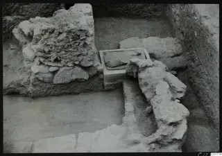 Excavation trench at Kition with a rectangular carved stone block showing a relief fragment beside rubble walls