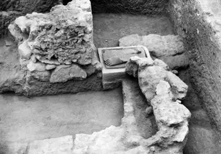 Excavation trench at Kition with a weathered stone sculpture in the foreground and a block carrying a carved foot