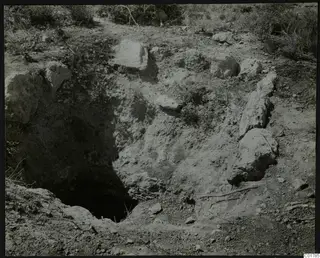 Excavation site at Kountoura Trachonia with a dark hollow in the ground and large stones around it