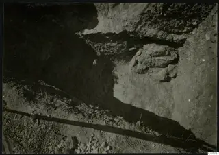 Excavation trench at Kountoura Trachonia with a projecting rock outcrop and stones in the cut face