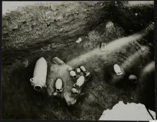 In situ pottery vessels and stones in an excavated trench at Ayia Irini