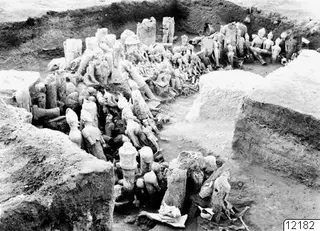 Excavated trench at Ayia Irini with many terracotta figurines and sculptures packed together in front of an altar