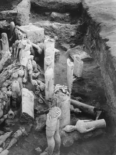 Excavation trench at Ayia Irini with many pale clay figures lying and standing among the earth