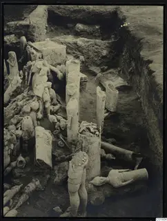 Excavation trench at Ayia Irini with many pale clay figurines and vessels lying in situ among the soil