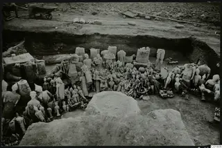 Excavated trench at Ayia Irini with a dense heap of clay figurines and sculpture fragments lying among stone blocks