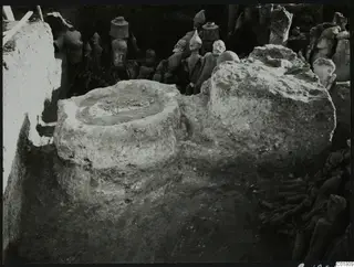 Terracotta figures found in situ in an excavation trench at Ayia Irini, beside a round stone basin.