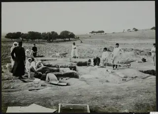 Workers in excavation trenches at Ayia Irini, with wheelbarrows, wooden boxes and a sieve frame on the ground