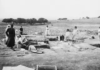 Workers in a trench at Ayia Irini, with wheelbarrows, buckets and a sieve on the excavation ground