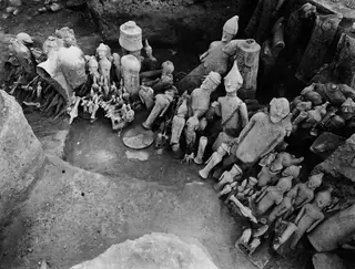 Excavated square at Ayia Irini with many terracotta figurines and vessels lying in the ground.