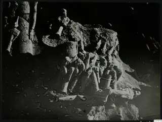 Pale stone sculpture fragments, including arms and legs, lying in excavated ground in grid square L 10 at Ayia Irini.