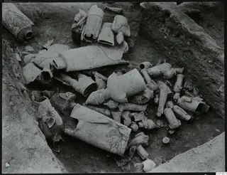 Excavated trench at Ayia Irini with many broken terracotta figurine fragments lying in the soil.