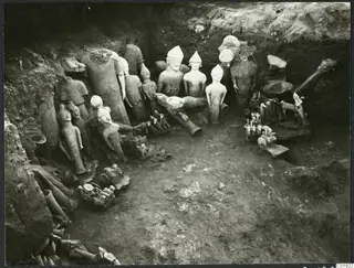 Statues and fragments found in situ in an excavation trench at Ayia Irini, pale figures among broken limbs and soil