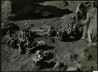Clay figurines and a bowl lying in situ in excavated ground at Ayia Irini