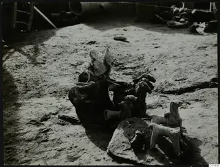 Terracotta figurines and animal figures lying in situ on a dusty excavation floor at Ayia Irini.