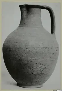 Pottery jug with a tall neck, single strap handle and rounded body, shown against a pale background.