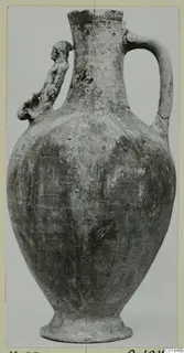 Pottery jug with a broken neck, a strap handle on the right and a modelled handle on the left, on a grey background