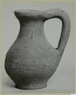 Pottery jug with a single loop handle and a flat rim, photographed on a plain background.