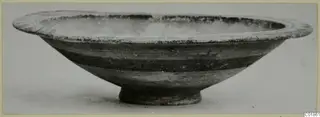 Shallow bowl with a wide rim and dark horizontal bands on the body, seen from the side.