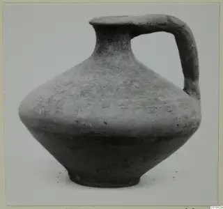 Black-slipped jug with a single loop handle, photographed against a plain grey background