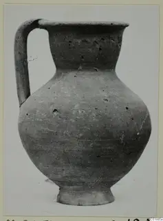 Plain pottery jug with a strap handle and wide rounded body, photographed against a pale background.