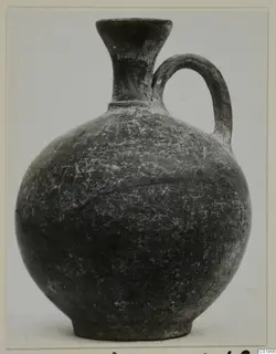 Pottery Stroke Polished Ware jug with a single loop handle and a flaring neck, dark surface